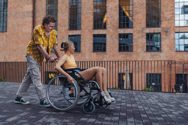 Beautiful gen Z girl in a wheelchair with her boyfriend. Inclusion, equality, and diversity among Generation Z. - HPIF32307