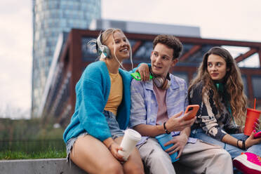 Generation z students hanging out together outdoors in the city. Young stylish zoomers are online, using smartphones, social media, taking selfies. Concept of power of friendship and social strength of gen Z. - HPIF32309