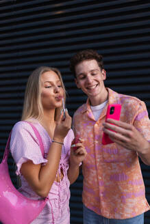 Gen Z couple in pink outfit taking selfie before going the cinema to watch movie. The young zoomer girl and boy watched a movie addressing the topic of women, her position in the world, and body image. - HPIF32312