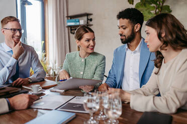 Young colleagues having casual discussion during meeting in office. Group of men and women sitting in conference room. - HPIF32321