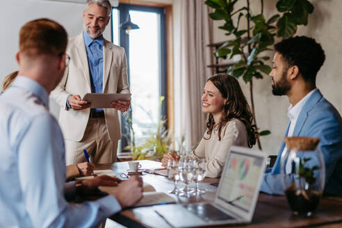 Businessman giving a presentation in a business meeting. Young colleagues and manager having casual discussion during meeting, workshop in office. - HPIF32331