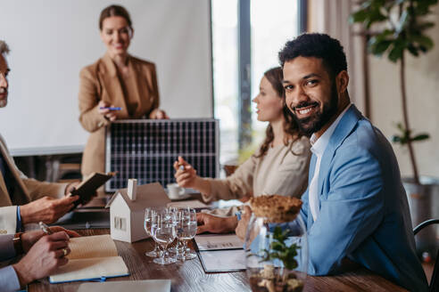 Female business leader giving a presentation about solar energy. Young colleagues discussing photovoltaic panels, clean, green, energy. Business using renewable energy. - HPIF32334