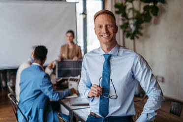 Portrait of confident young businessman during team meeting. Young colleagues discussing photovoltaic panels, clean, green, energy. Business using renewable energy. - HPIF32337