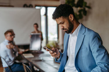 Portrait of confident young businessman using smart phone during meeting.Young colleagues discussing photovoltaic panels, clean, green, energy. Business using renewable energy. - HPIF32348