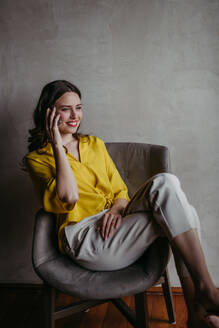 Portrait of a young businesswoman sitting near window in modern office full of plants. Female corporate leader, executive, manager making phone call. - HPIF32382