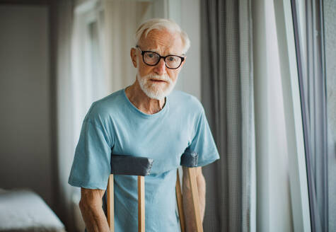 Portrait of an elderly man with crutches at home. - HPIF32405