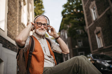 Nahaufnahme eines älteren Mannes auf der Straße. Älterer, cooler Mann, der im Freien Musik hört und Spaß hat. Konzept eines alten, jung gebliebenen Mannes. - HPIF32431