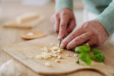 Close up of senior man cutting a garlic. - HPIF32457