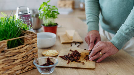 Close up of senior man cutting a dried tomatoes. - HPIF32469