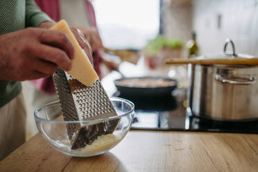 Close up of a senior man grating cheese during cooking. - HPIF32477