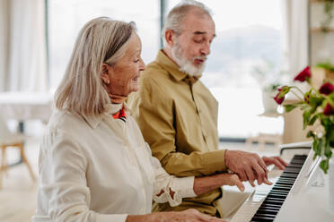 Senior couple playing on piano together in their livingroom. - HPIF32487