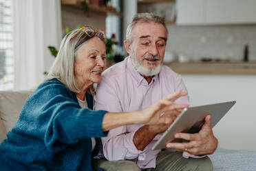 Senior couple scrolling tablet in the livingroom. - HPIF32493