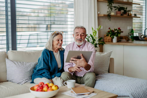 Senior couple scrolling tablet in the livingroom. - HPIF32494