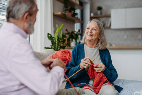 Senior couple knitting together in the living room. - HPIF32496