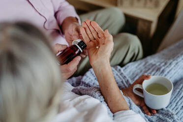 Close up of senior man giving pills to his ill wife. - HPIF32511