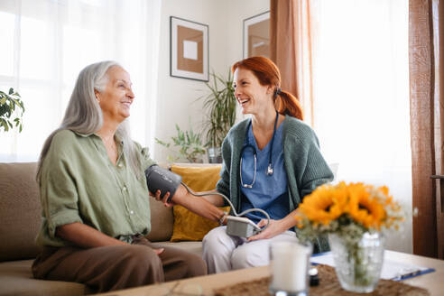 Krankenschwester misst Blutdruck bei einer älteren Frau in ihrem Haus. - HPIF32521