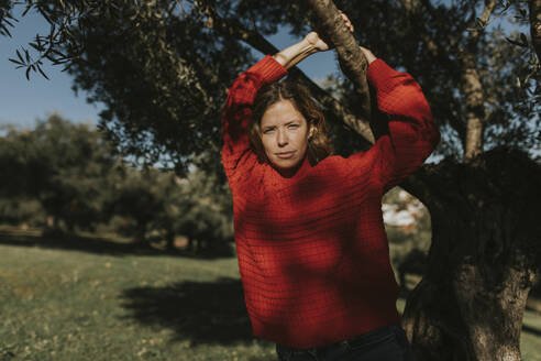Frau hängt an einem Olivenbaumzweig im Feld - DMGF01141