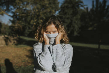 Woman covering face with turtleneck sweater - DMGF01151