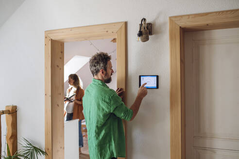 Mann stellt die Temperatur über eine App auf einem Tablet-PC zu Hause ein - HAPF03508