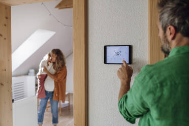 Ein Mann steuert die Temperatur über eine Hausautomatisierungs-App auf einem Tablet-PC - HAPF03513