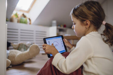Girl controlling temperature through app on tablet PC in attic - HAPF03540