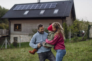 Glückliche Eltern, die sich mit ihrer Tochter vor dem Haus vergnügen - HAPF03544