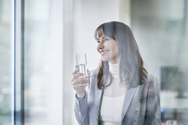 Glückliche Geschäftsfrau mit einem Glas Wasser in der Hand - RORF03639