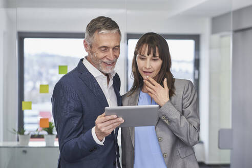 Smiling mature businesswoman having discussion with businessman in office - RORF03655