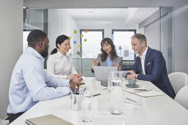 Businesswoman discussing with colleagues over laptop at desk - RORF03665