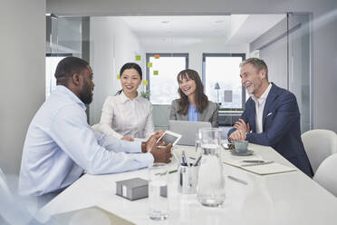 Happy business people having discussion at desk in office - RORF03666