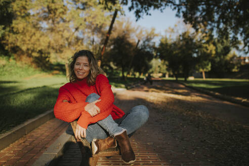 Smiling woman sitting in park - DMGF01162