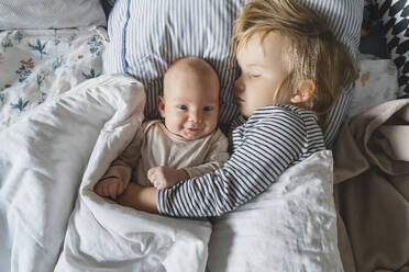 Baby Junge lächelnd in der Nähe von Schwester schlafen im Bett zu Hause - NDEF01460