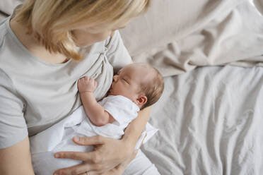 Mutter stillt neugeborenen Sohn im Arm auf dem Bett - NDEF01462