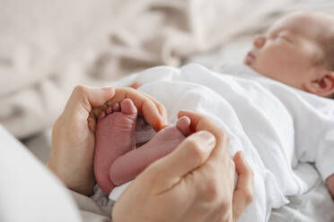 Mother holding newborn son's feet in hand - NDEF01464