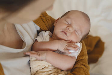 Neugeborener Junge schläft zu Hause in den Armen seiner Mutter - NDEF01484