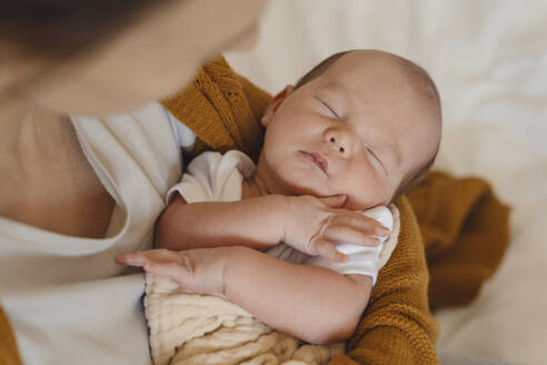 Newborn baby boy sleeping in mother's arms at home - NDEF01484