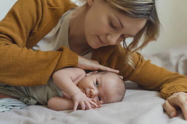 Woman caressing newborn son lying on bed at home - NDEF01491