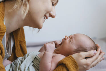 Happy mother holding baby boy in arms at home - NDEF01493