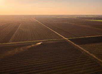 Serbia, Vojvodina Province, Aerial view of tractor sowing seeds at dusk - NOF00825