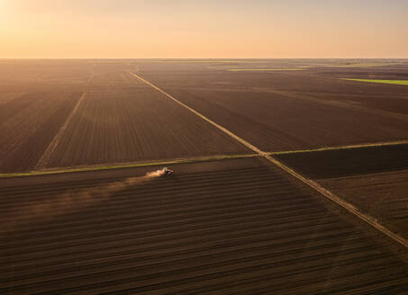 Serbia, Vojvodina Province, Aerial view of tractor sowing seeds at dusk - NOF00825