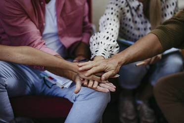 People at community meeting stacking hands to symbolize unity - HAPF03572