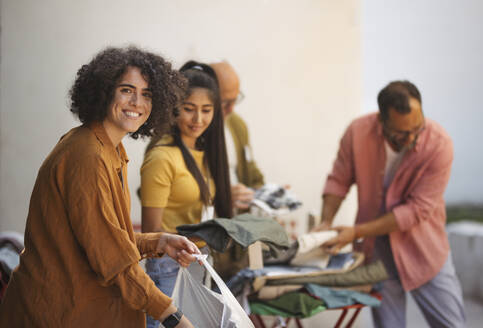 Smiling women donating used clothes for charity - HAPF03592