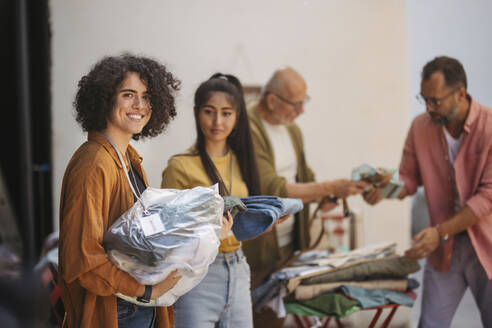 Lächelnde Frauen spenden gebrauchte Kleidung für wohltätige Zwecke - HAPF03593