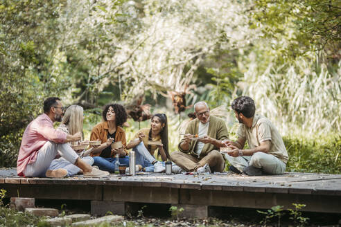 Freiwillige Helfer bei einem Gemeinschaftsprojekt essen gemeinsam im Gemeinschaftsgarten - HAPF03635