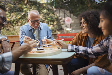 Freunde sitzen im Garten und haben Spaß beim Essen von Sushi mit Stäbchen - HAPF03651