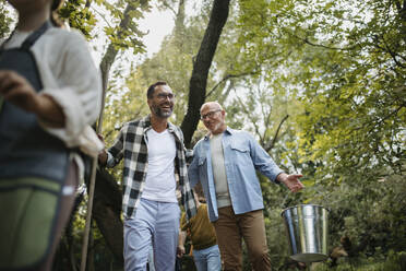 Zwei Männer mit Besen und Eimern nehmen an einer Aufräumaktion in einem Park teil - HAPF03684