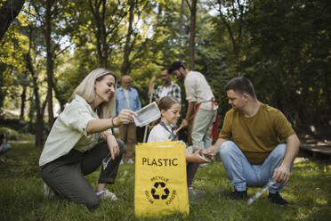 Sozial integrative Gruppe von Freiwilligen, die Plastikabfälle in Recyclingsäcke füllen - HAPF03696