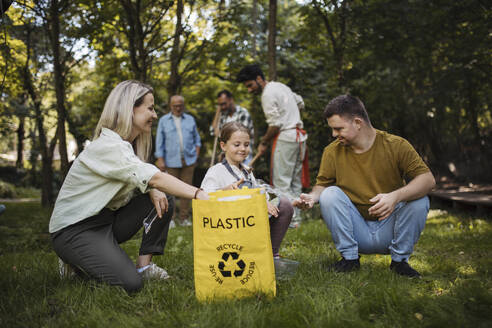 Sozial integrative Gruppe von Freiwilligen, die Plastikabfälle in Recyclingsäcke füllen - HAPF03698