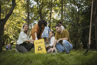 Sozial integrative Gruppe von Freiwilligen, die Plastikabfälle in Recyclingsäcke füllen - HAPF03699
