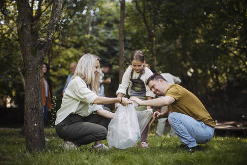 Socially inclusive group of volunteers collecting plastic waste in public park - HAPF03701